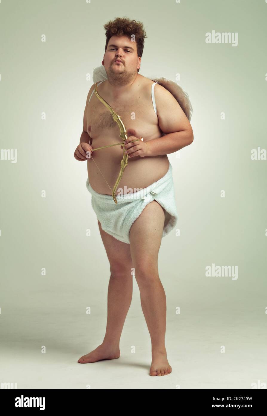Aiming for you. An obese man dressed as a cherub with a bow and arrow. Stock Photo