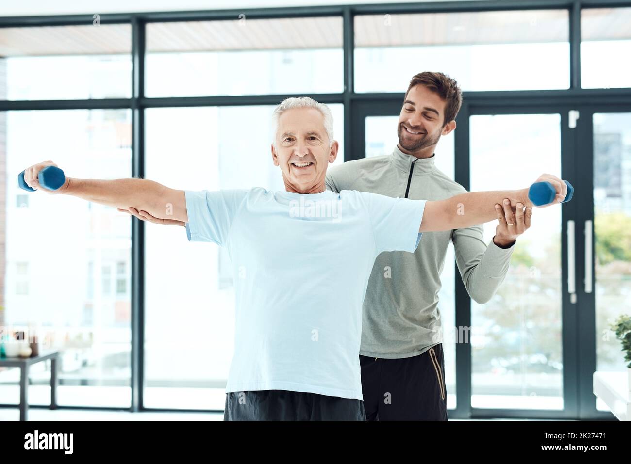 I'm working on being more independent. Shot of a friendly physiotherapist helping his senior patient work out with weights. Stock Photo
