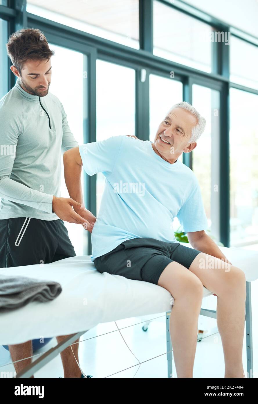 This is where I feel discomfort. Shot of a senior man consulting with his physiotherapist. Stock Photo