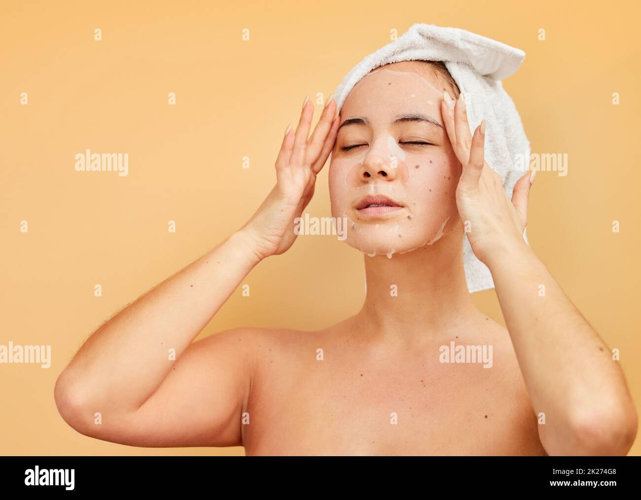 Make time to treat yourself. Shot of a young woman applying a face mask during her morning beauty routine against a yellow background. Stock Photo