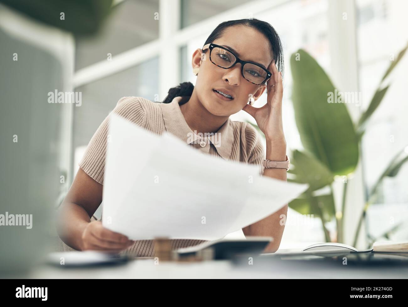 This is so complicated and confusing. Portrait of a young businesswoman looking stressed out while calculating finances in an office. Stock Photo