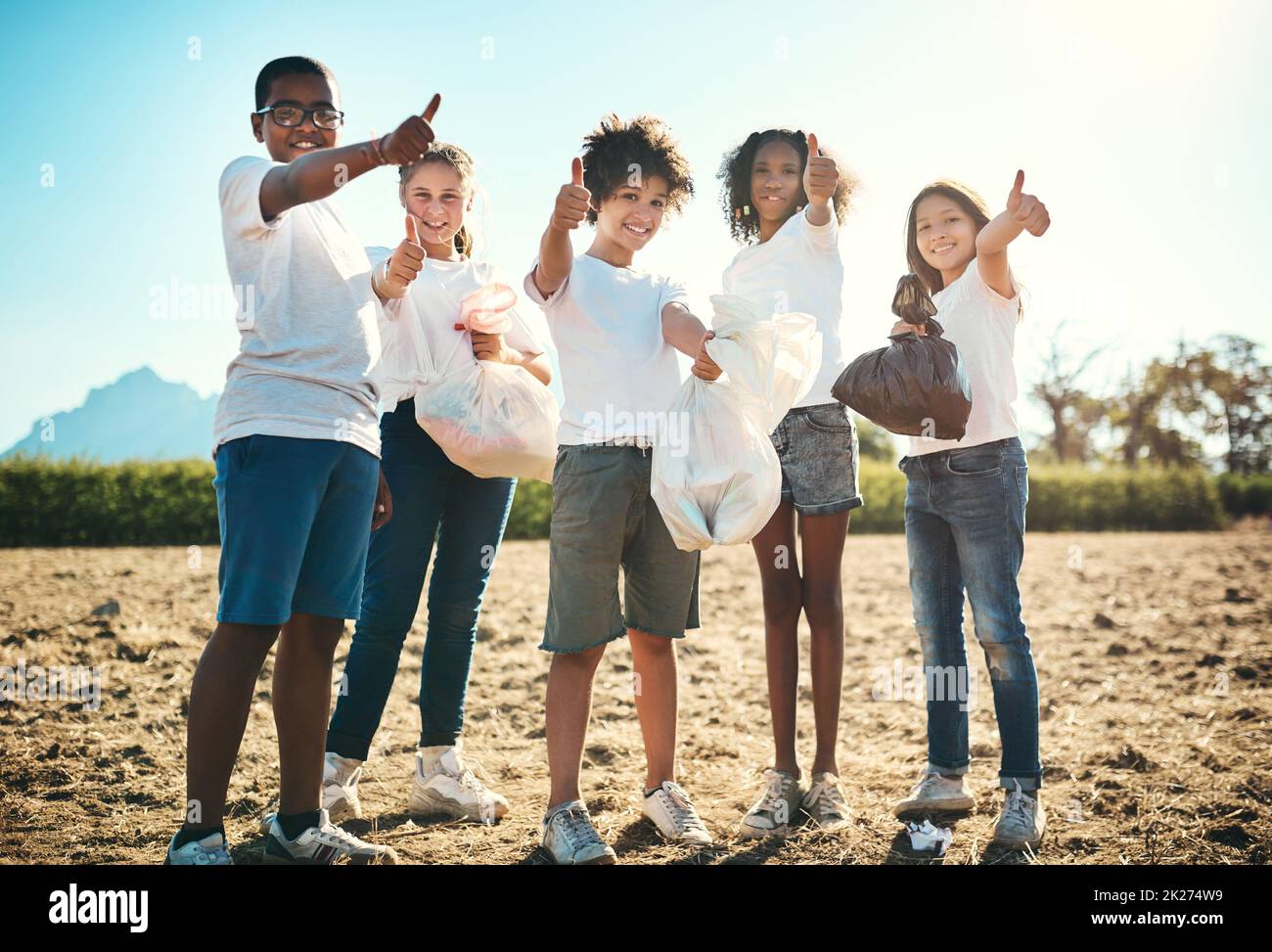 Shot of a group of teenagers picking up litter off a field and showing