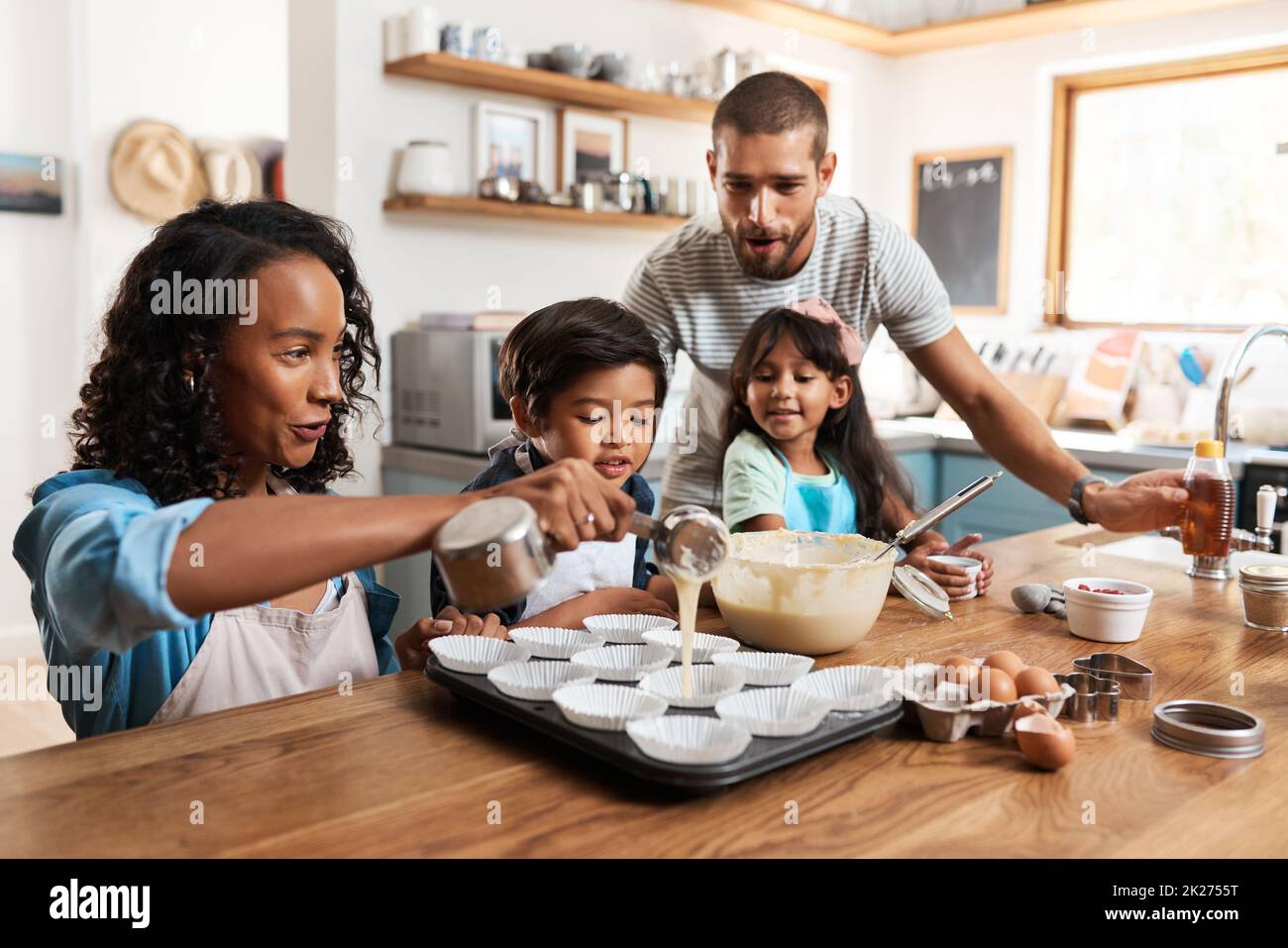 This is where the magic starts. Cropped shot of a young couple baking at home with their two children. Stock Photo