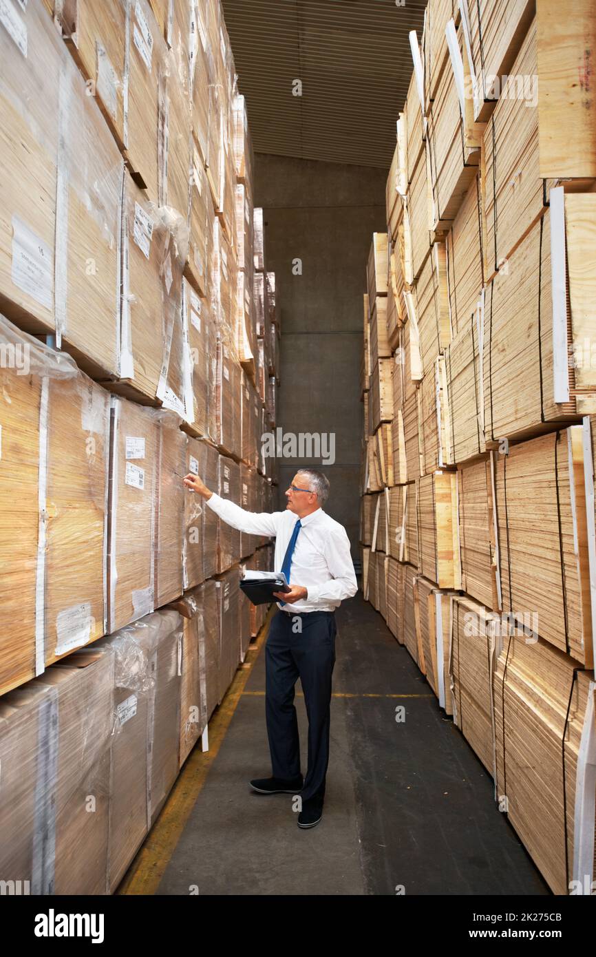 Dedicated warehouse worker. A manager standing in an aisle in a warehouse examining the