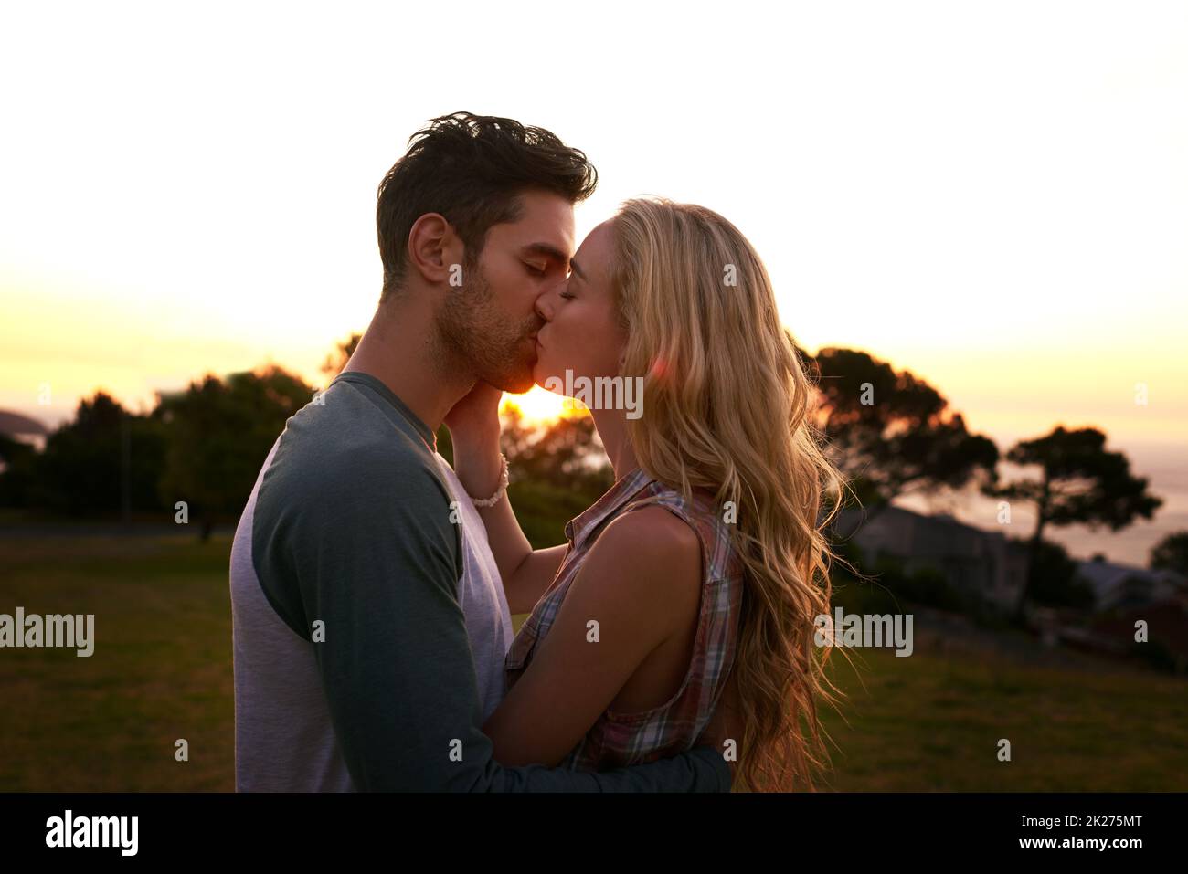 Smooches at sunset. Cropped shot of an affectionate young couple outdoors. Stock Photo