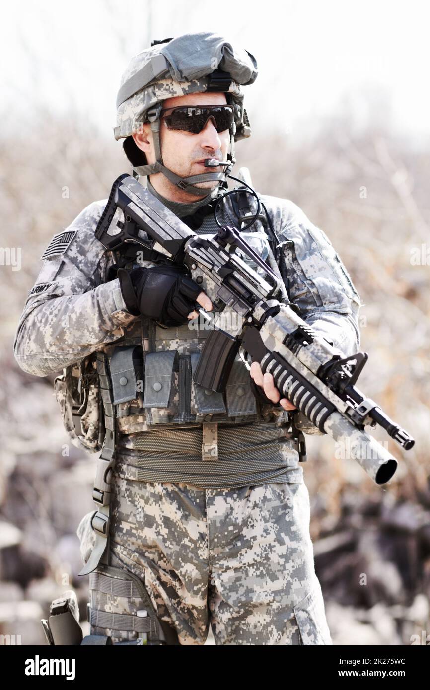 Warrior of war. A soldier standing with gun in hand in a desert environment. Stock Photo
