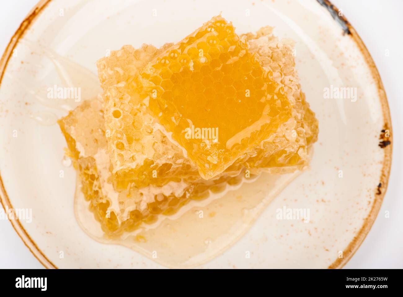 Close up stack of several fresh cut golden comb honey slices on plate isolated on white background, elevated top view, directly above Stock Photo