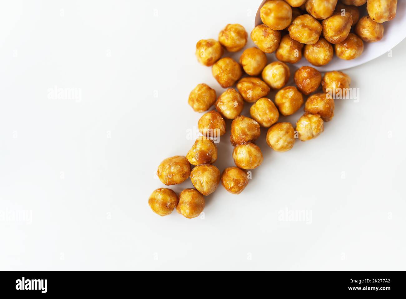 Scattered hazelnuts in caramel on a white background. Very tasty and healthy and highcalorie