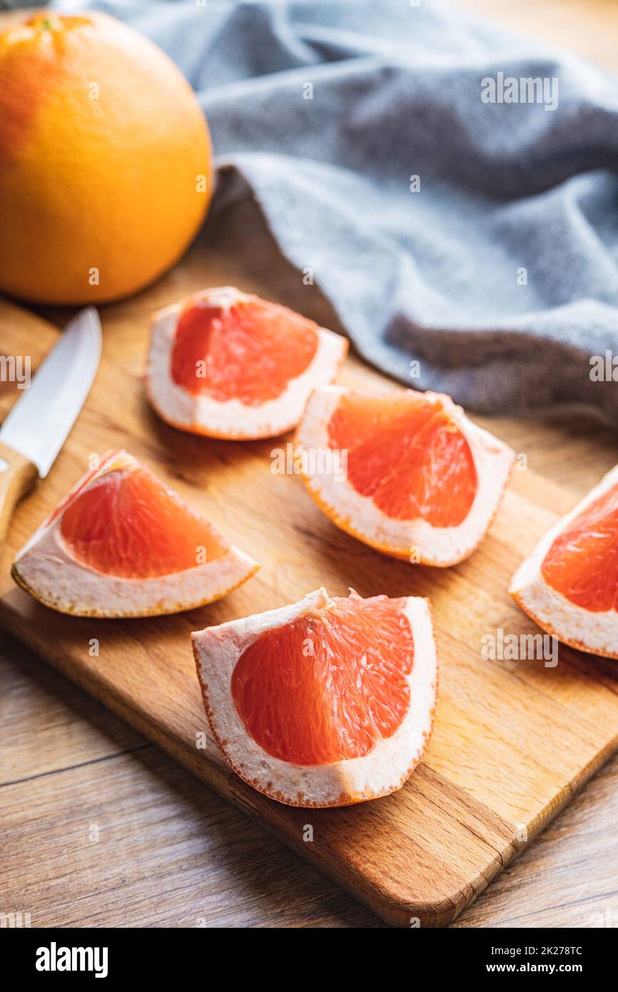 Sliced citrus fruit. Chopped fresh grapefruit on cutting board. Stock Photo