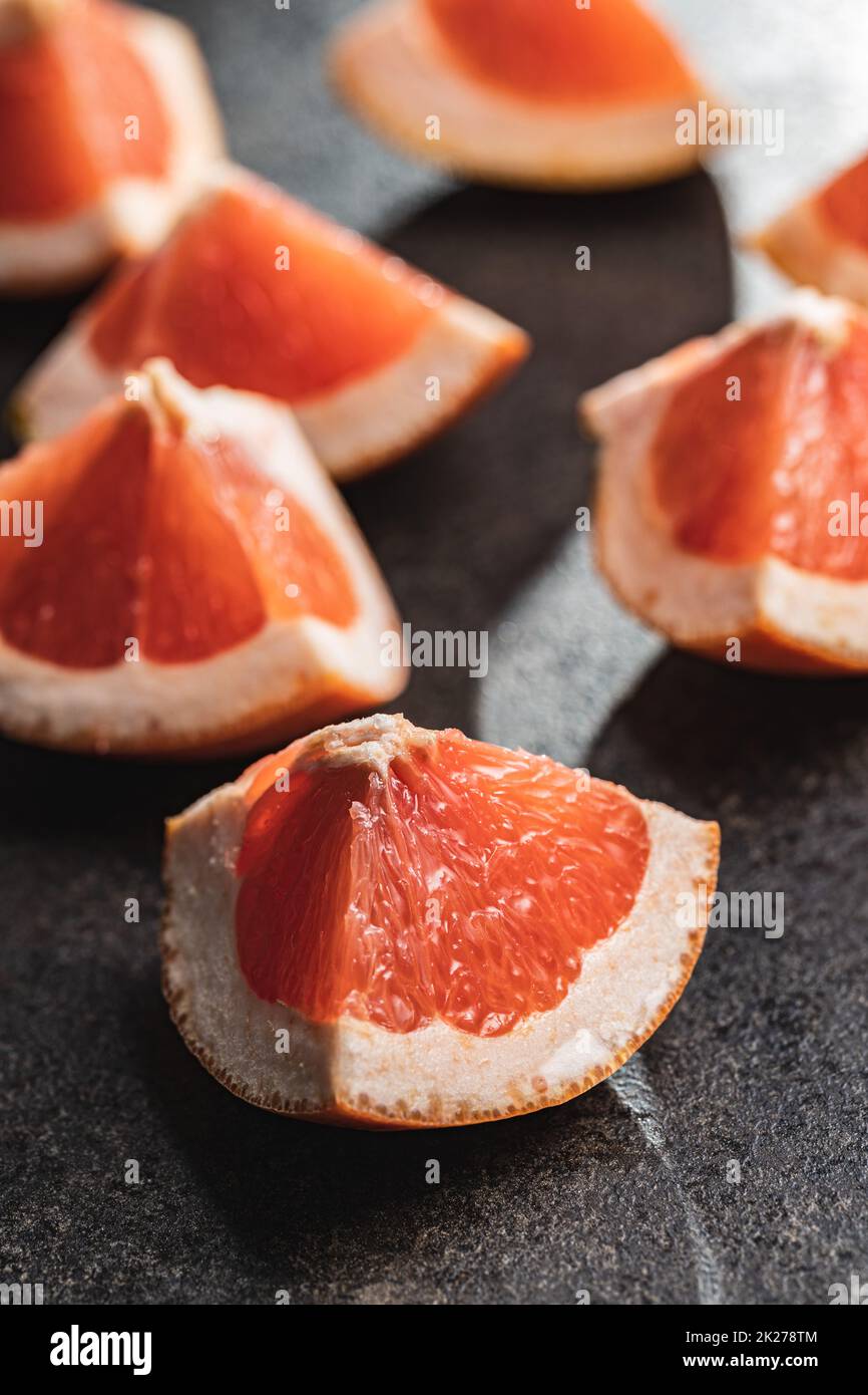 Sliced citrus fruit. Chopped fresh grapefruit on black table. Stock Photo