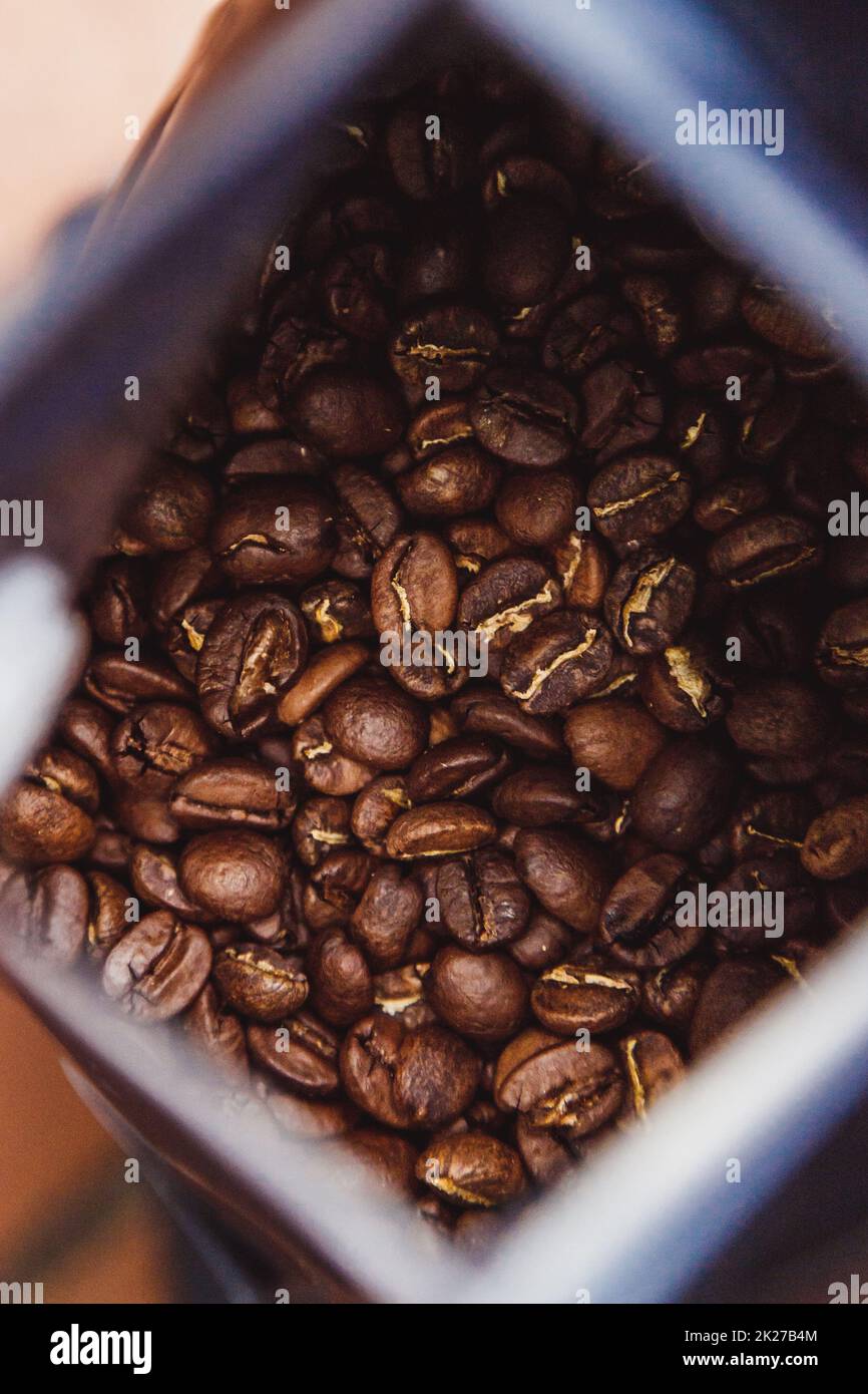 Coffee beans in a plastic foil package on wooden background. Roasted aromatic coffee top view. Stock Photo