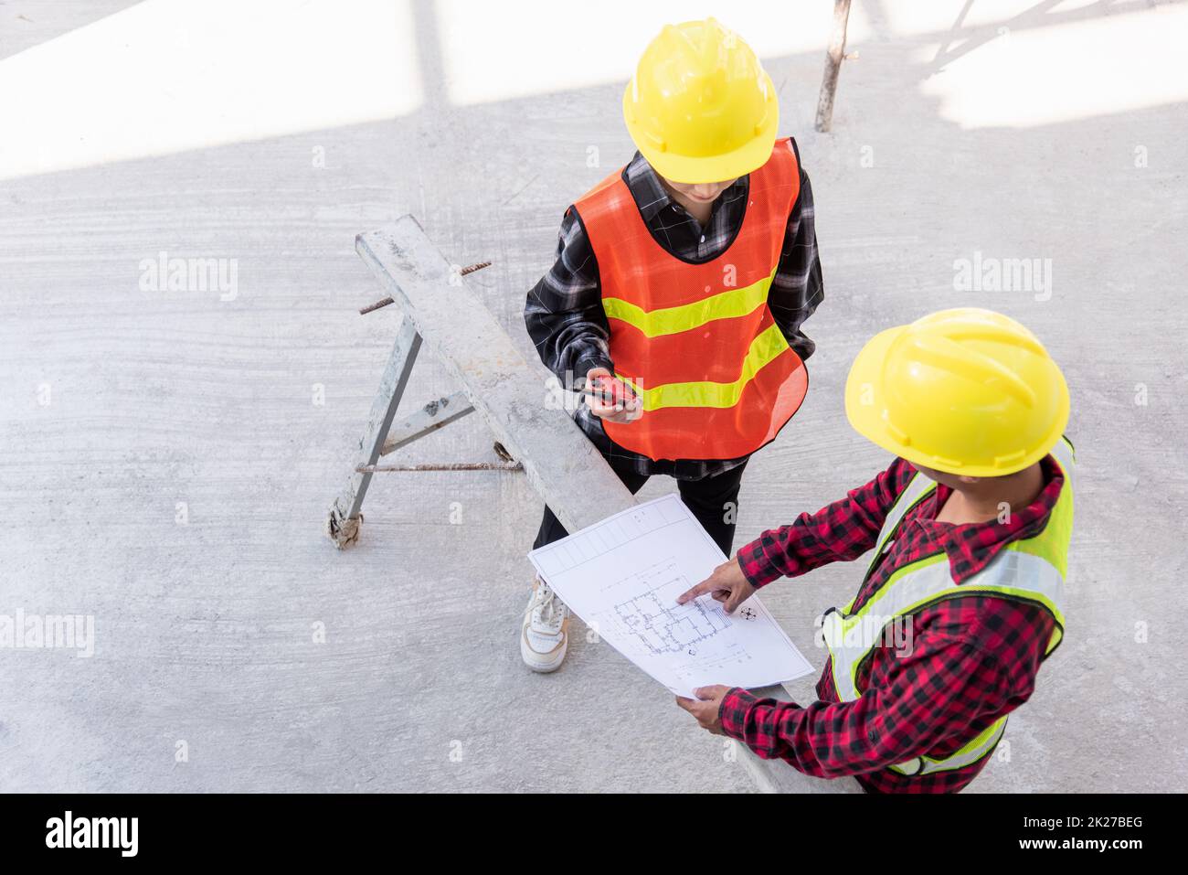 Architect and client discussing help create plan with blueprint of the building at construction site floor. Asian engineer foreman worker man and woman meeting and planning construction work, top view Stock Photo