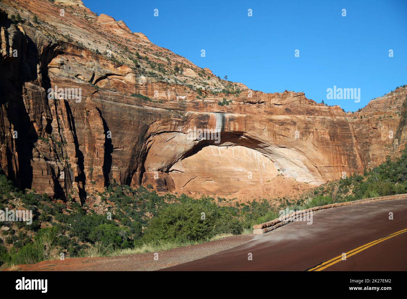 The arch shaped red mountain with the red paved road of Zion National Park Stock Photo