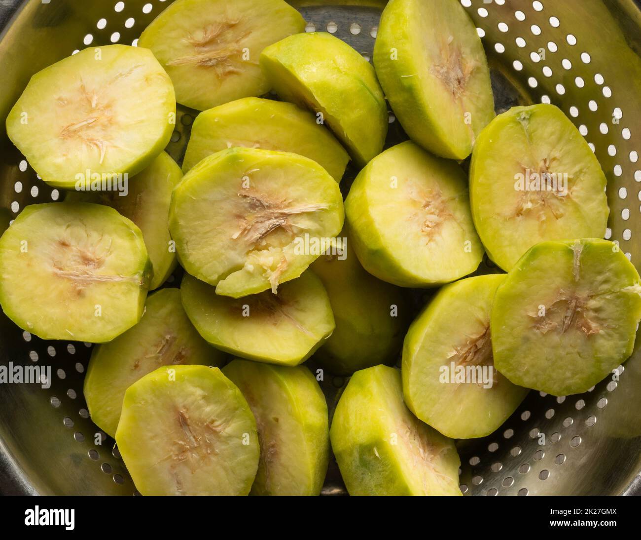 sliced ambarella or june plum, cut and peeled edible fruits in a bowl for making vegetarian condiment or sauce, close-up taken from above Stock Photo