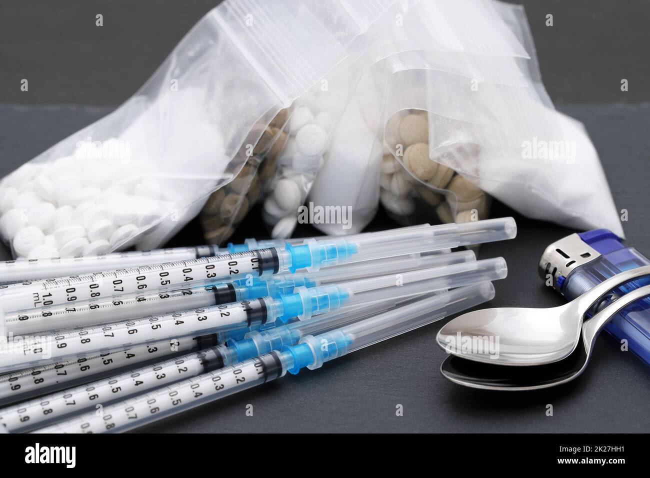 Drug injection syringe and cooked heroin in a bag on black table Stock Photo