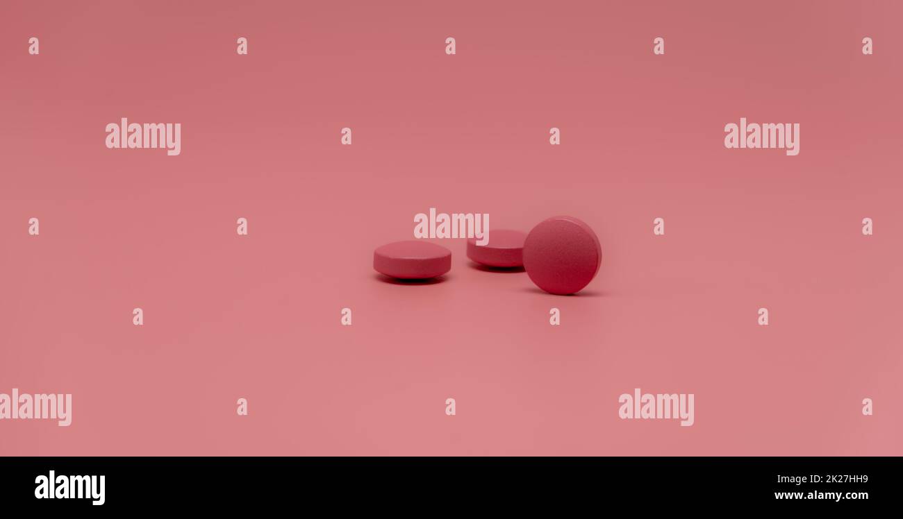 Selective focus on round pink tablet pill on pink background. Pharmacy horizontal web banner. Pharmaceutical industry. Prescription drug. World Health Day background. Vitamins and minerals concept. Stock Photo