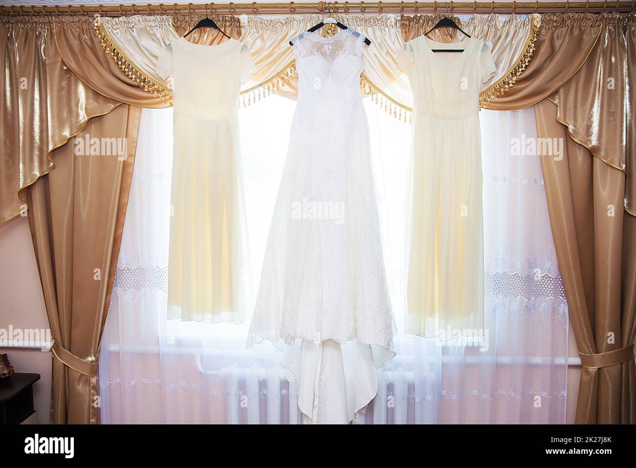 bride and bridesmaids dresses hanging on hangers Stock Photo