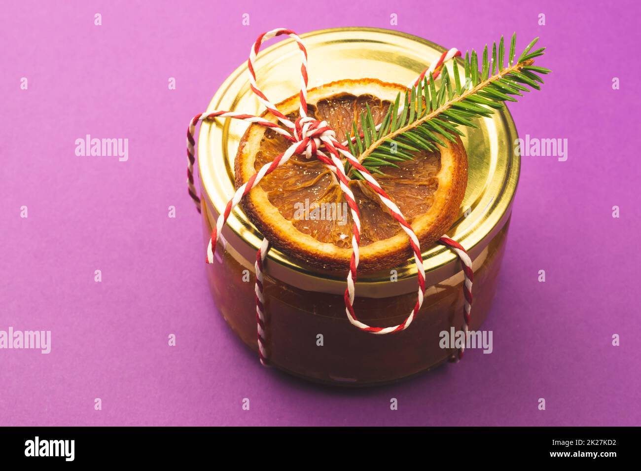 Homemade jam in a decorated jar with orange slice and fir tree twig. Winter gift Stock Photo