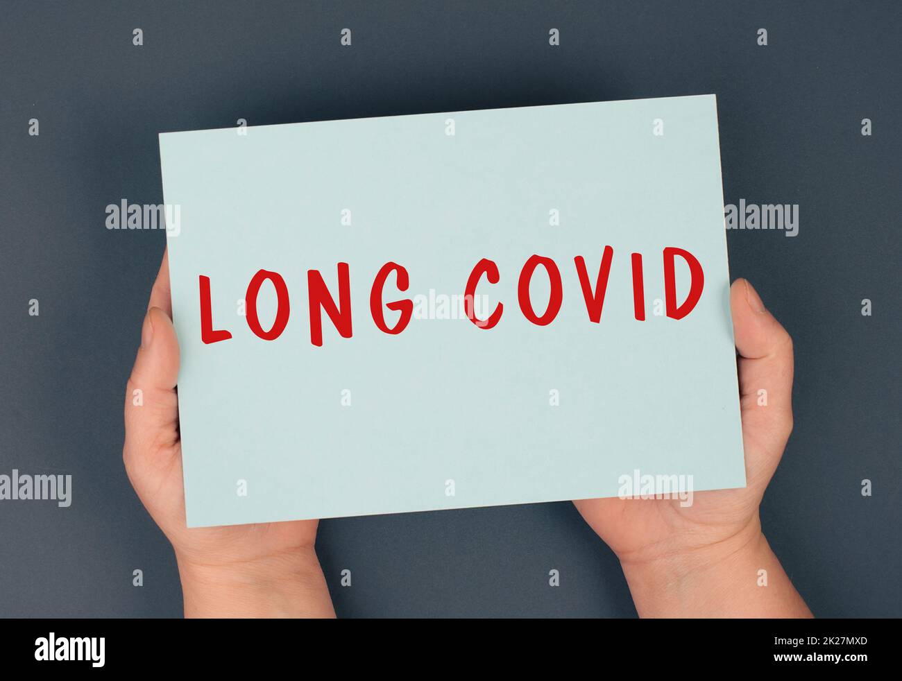 The words long covid are standing on a paper, hands hold the message, problems after covid-19 disease Stock Photo