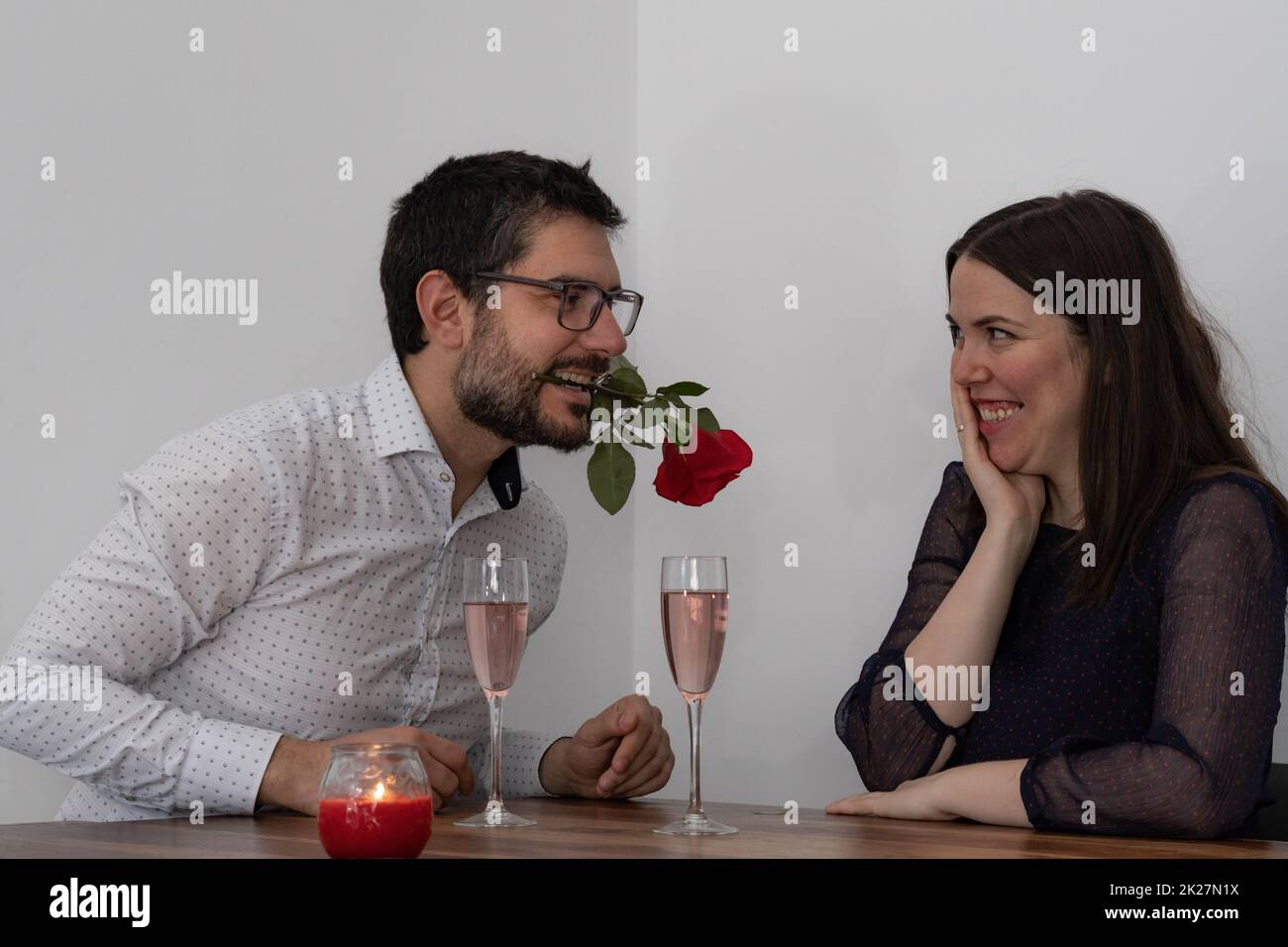 young man holding a rose in his mouth and his smiling girlfriend Stock Photo