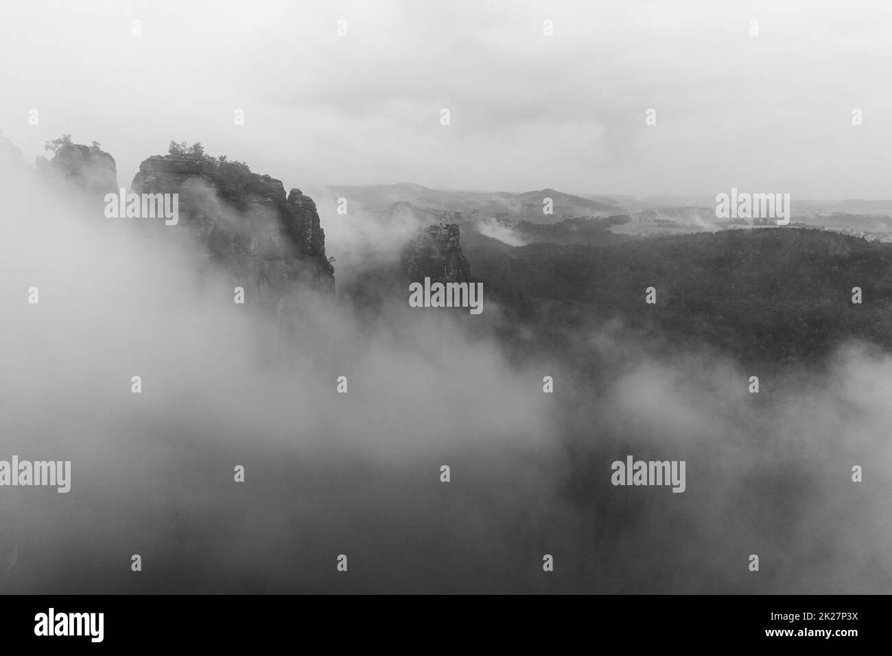 An early cloudy morning in mountain. Schrammsteine - group of rocks are a long, strung-out, very jagged in the Elbe Sandstone Mountains located in Saxon Switzerland in East Germany. Black and white. Stock Photo
