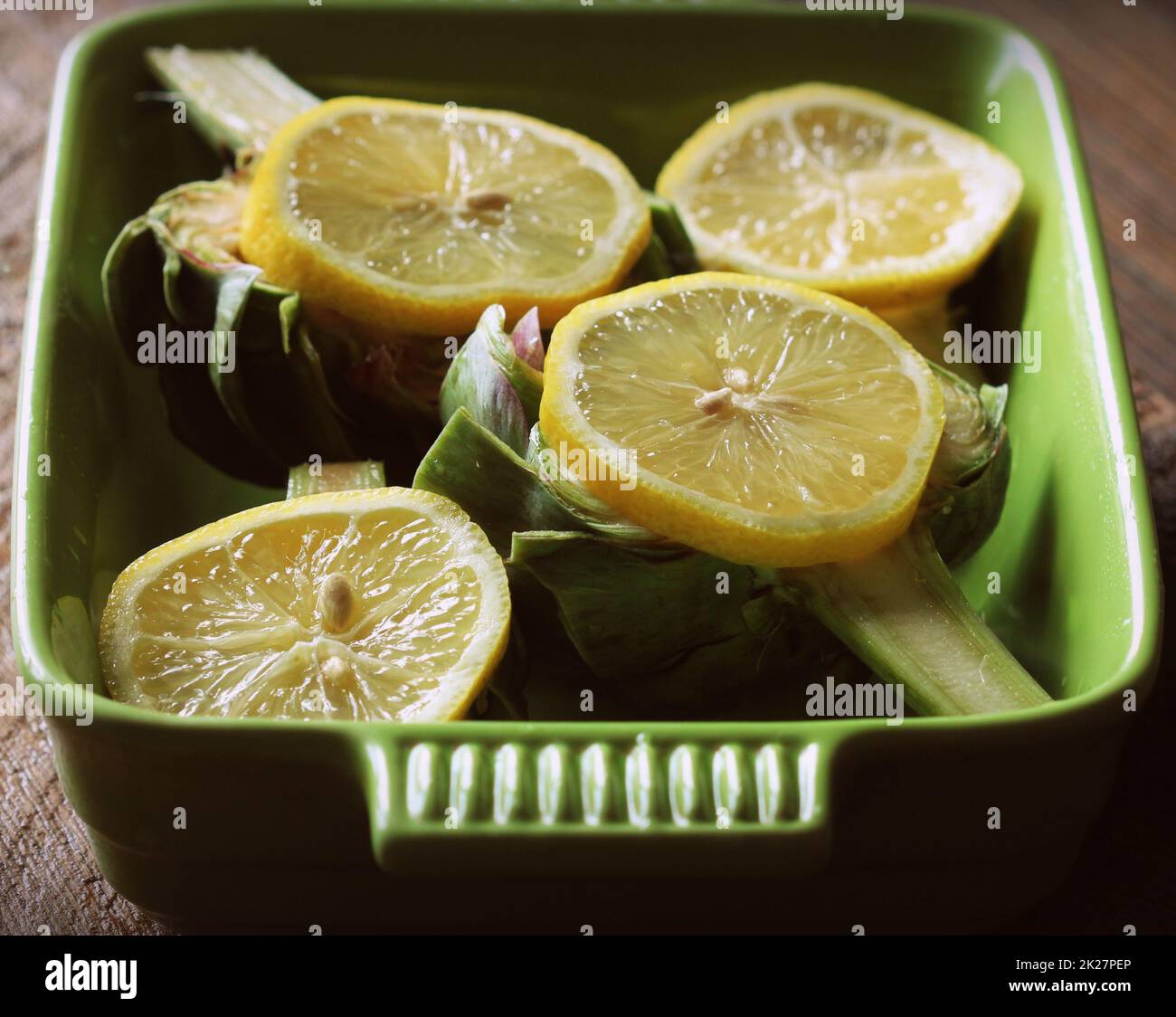 Artichokes recipe with garlic and lemon on pan . Ready for cooking