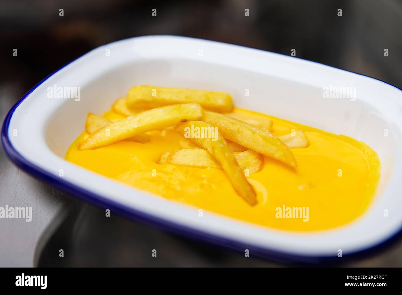 The concept of fast food and fast food. French fries sit in a plate along with cheddar cheese sauce. Top view, close-up. Stock Photo