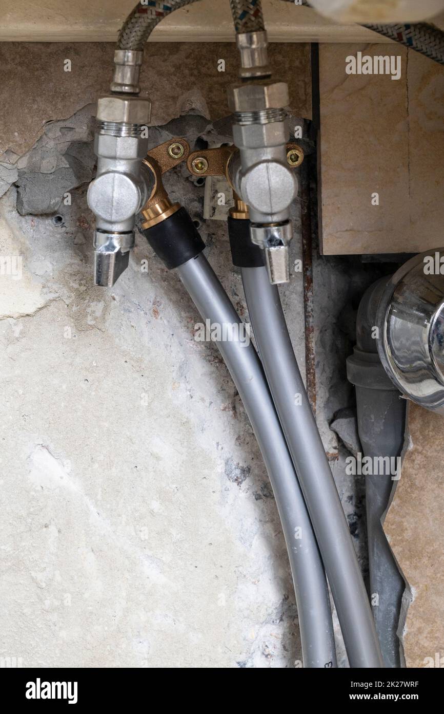 water pipes connected to valves inside wall Stock Photo