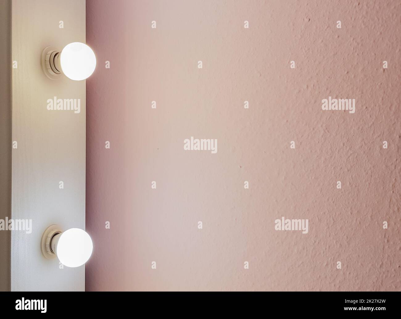 Modern new flat pink wall with two light bulbs from a large floor mirror for makeup and full-length shopping. Abstract modern trendy texture background. Copy space for your text. Stock Photo