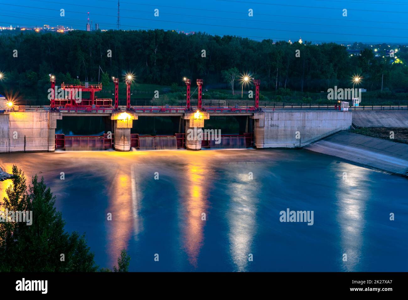 River,dam,bridge in the evening.Car and pedestrian bridge at night. A full-flowing river with a strong current.Clean,bubbling,fresh water.Technical construction on the river, fresh water reserves. Stock Photo