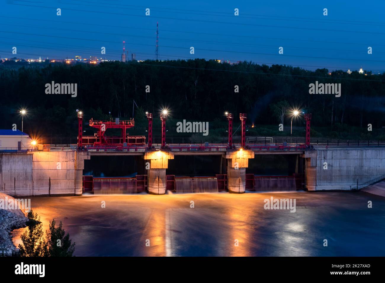 River,dam,bridge in the evening.Car and pedestrian bridge at night. A full-flowing river with a strong current.Clean,bubbling,fresh water.Technical construction on the river, fresh water reserves. Stock Photo