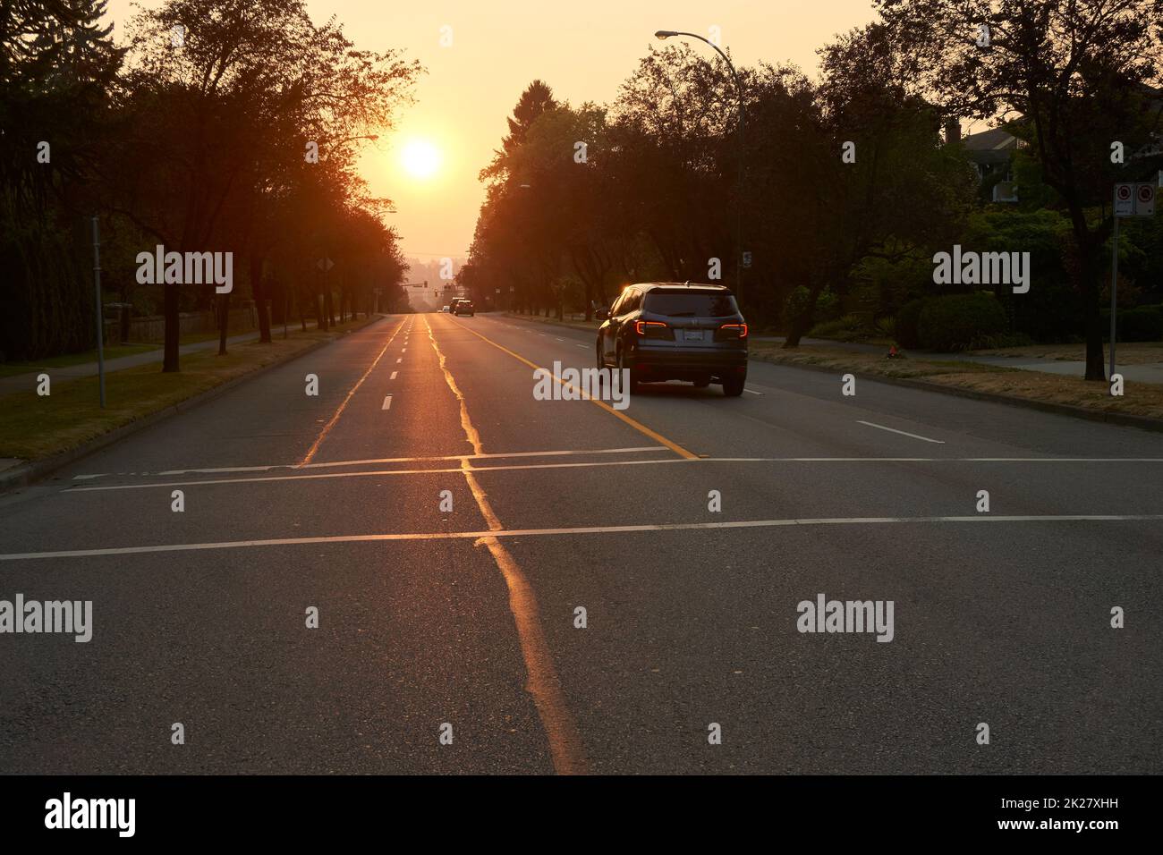 Cars on West 16th Avenue with setting sun in background, Vancouver, BC