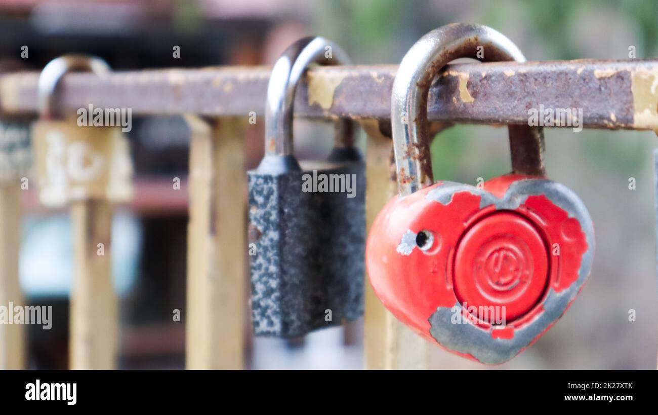 Shabby red lock in the shape of a heart. Valentine's day love concept. A padlock hanging on a metal railing is a sign of eternal love. The tradition of hooking a castle with a fence Stock Photo