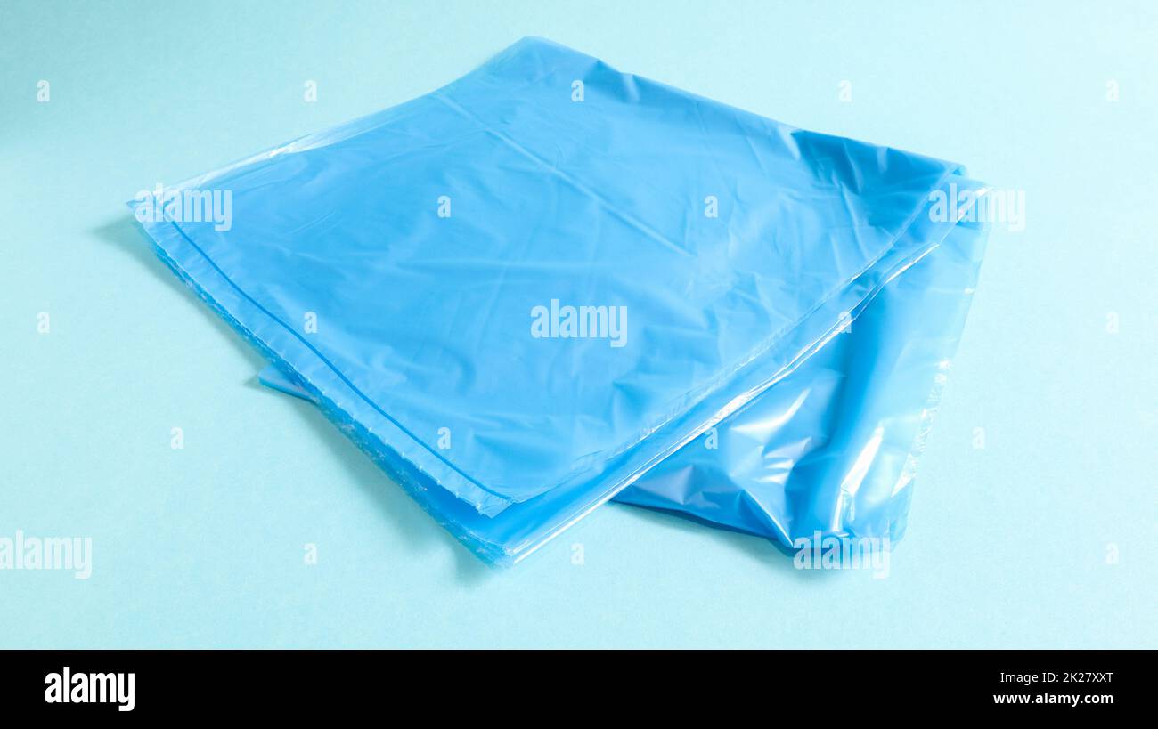 One torn plastic garbage bag in blue on a blue background. A bag that is designed to accommodate garbage in it and is used at home and placed in various garbage containers. Stock Photo
