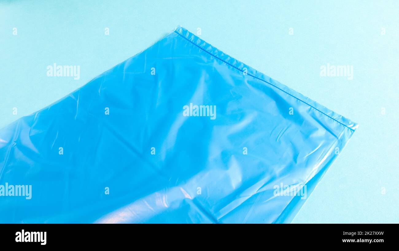 One torn plastic garbage bag in blue on a blue background. A bag that is designed to accommodate garbage in it and is used at home and placed in various garbage containers. Stock Photo