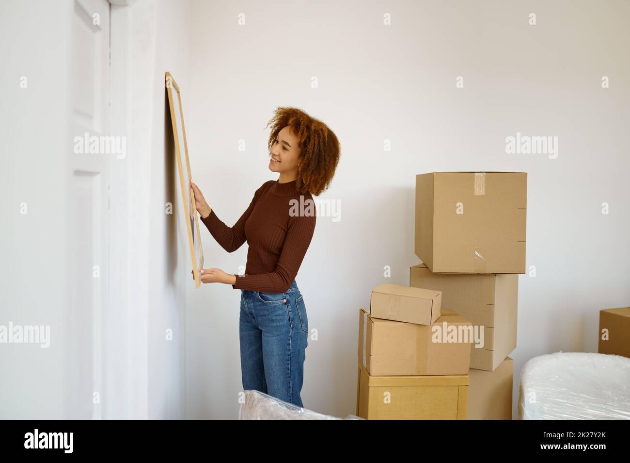 Woman hanging picture on the wall Stock Photo