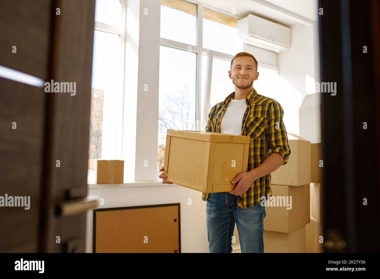 Young man carrying cardboard box during relocation Stock Photo
