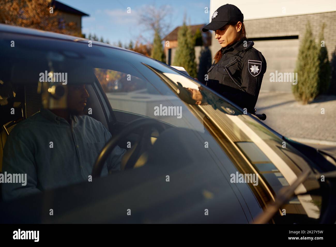 Young policewoman with tablet standing near car Stock Photo