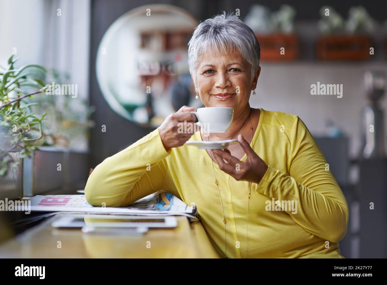 This is my favourite coffee shop. Portrait of a mature woman enjoying a warm beverage at a coffee shop. Stock Photo