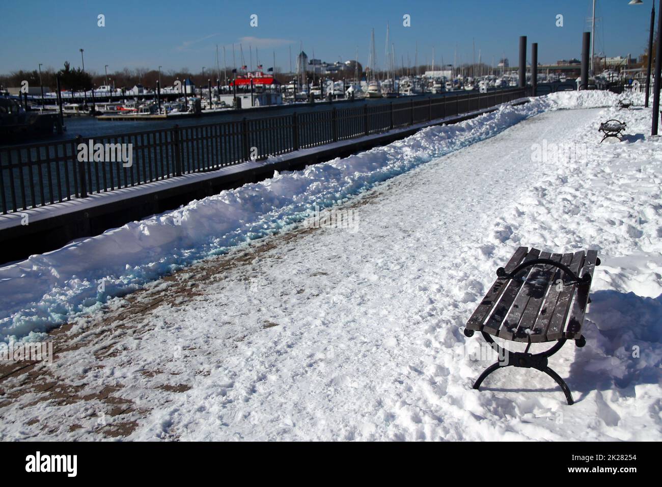 The path in the snow and the bench on the Morris Channel Basin Walkaway Stock Photo