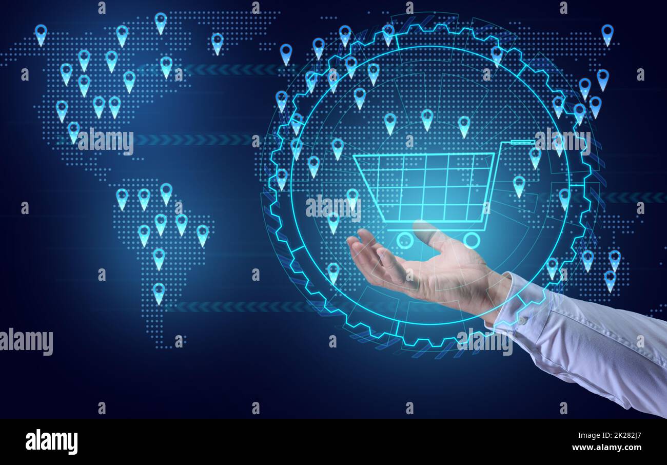 a man's hand holds a virtual shopping cart against the background of a world map with points of sale. Internet sales concept, profit growth due to market expansion Stock Photo