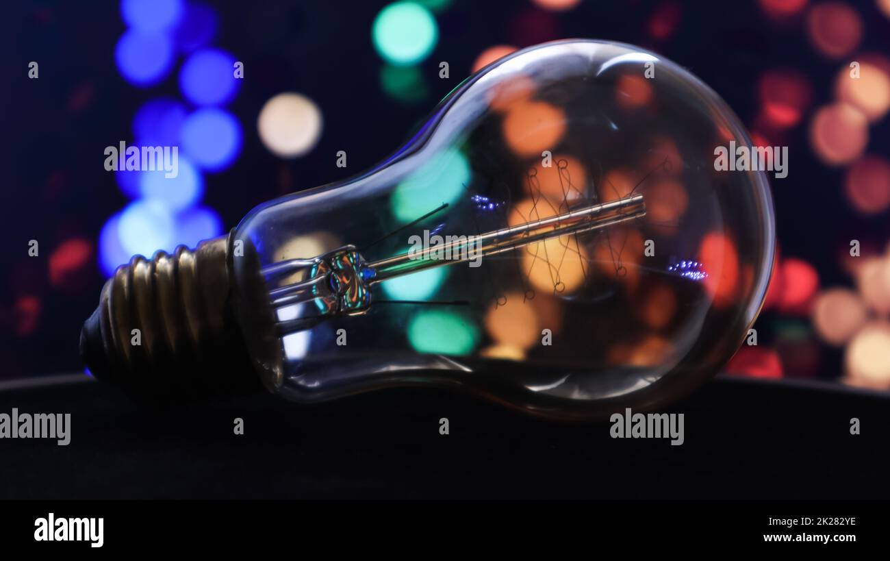 One light bulb lies on a black background with lights in the background. Creative ideas concept