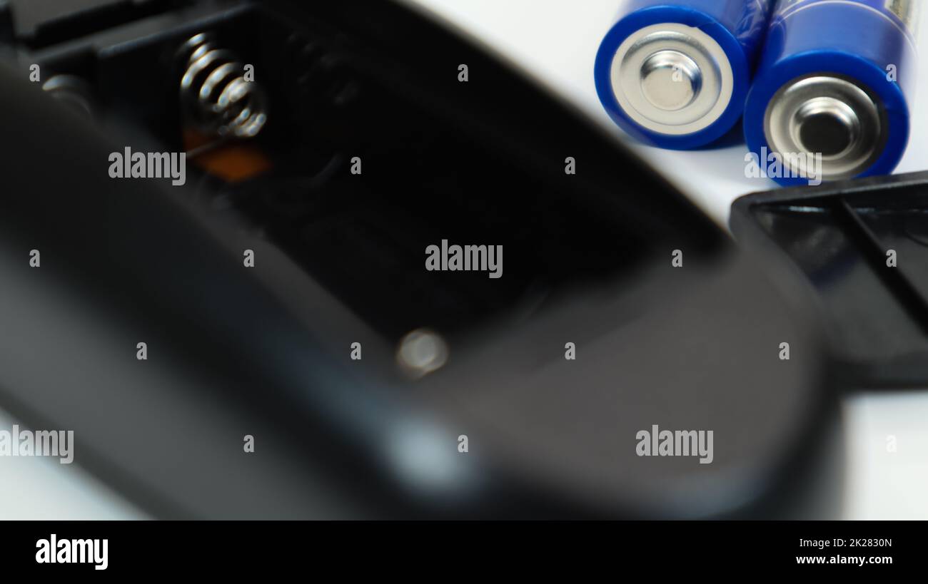 Black remote control with blue AAA batteries on a white background
