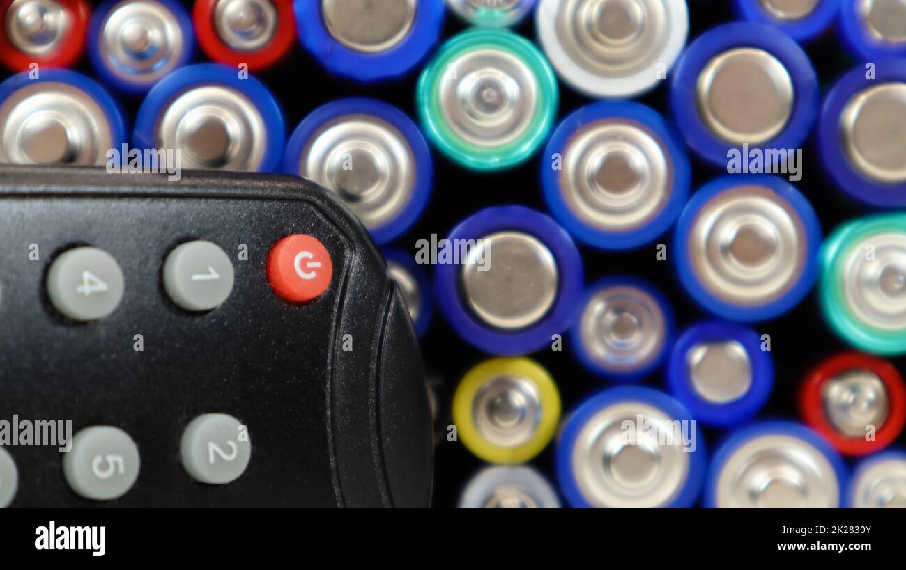 TV remote control with disposable AAA and AA alkaline batteries. Battery replacement, spare parts. Recycling concept. Lots of batteries. Stock Photo
