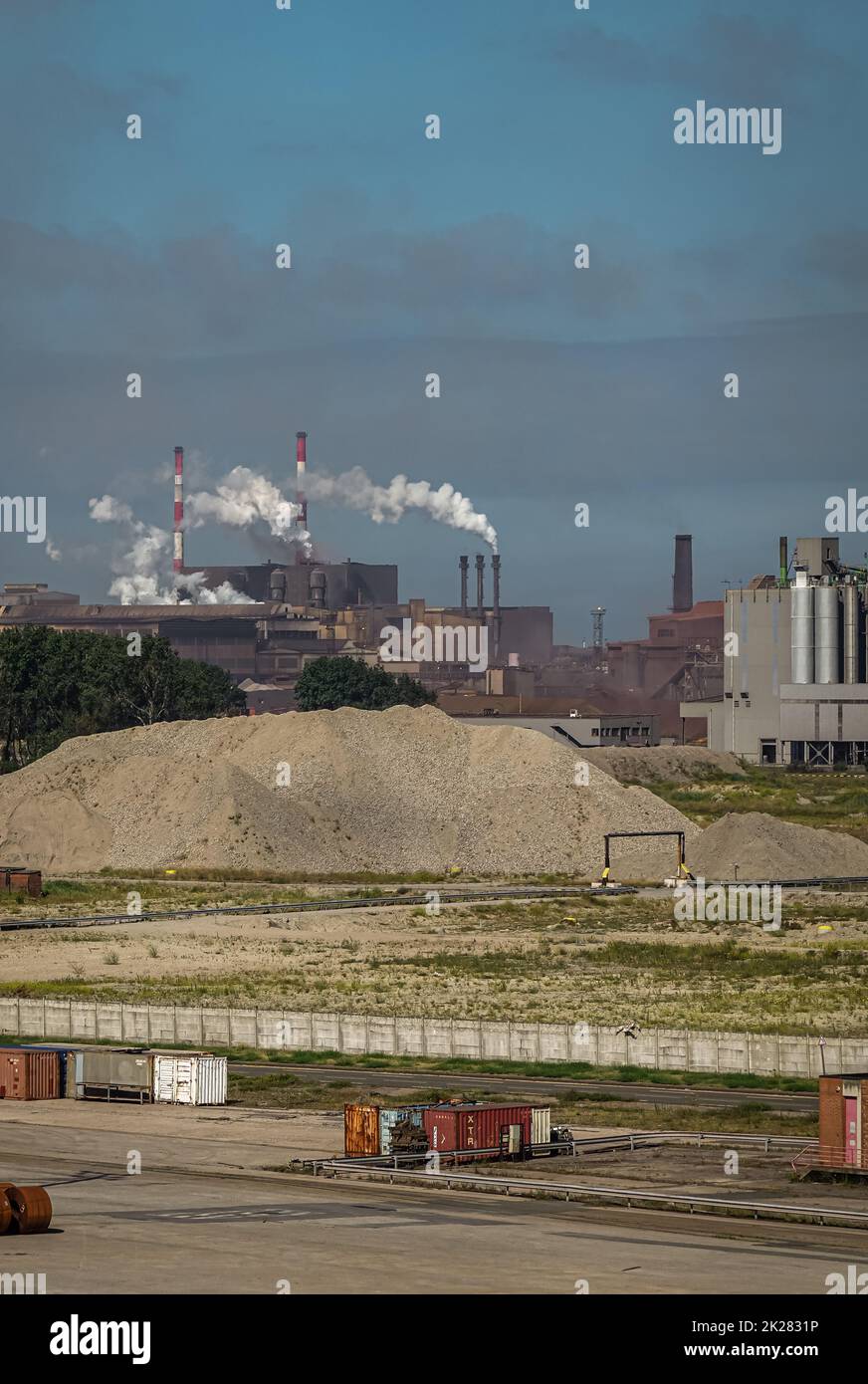 Europe, France, Dunkerque - July 9, 2022: Port scenery. Chimneys blow smoke over large power generation plant under smokey sky. Other port scenery up Stock Photo