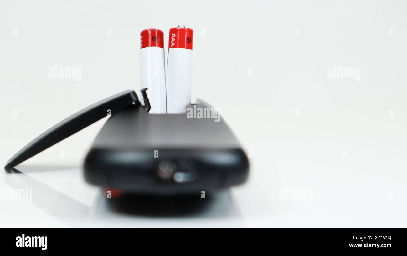 Black TV remote control with AAA alkaline batteries on a white