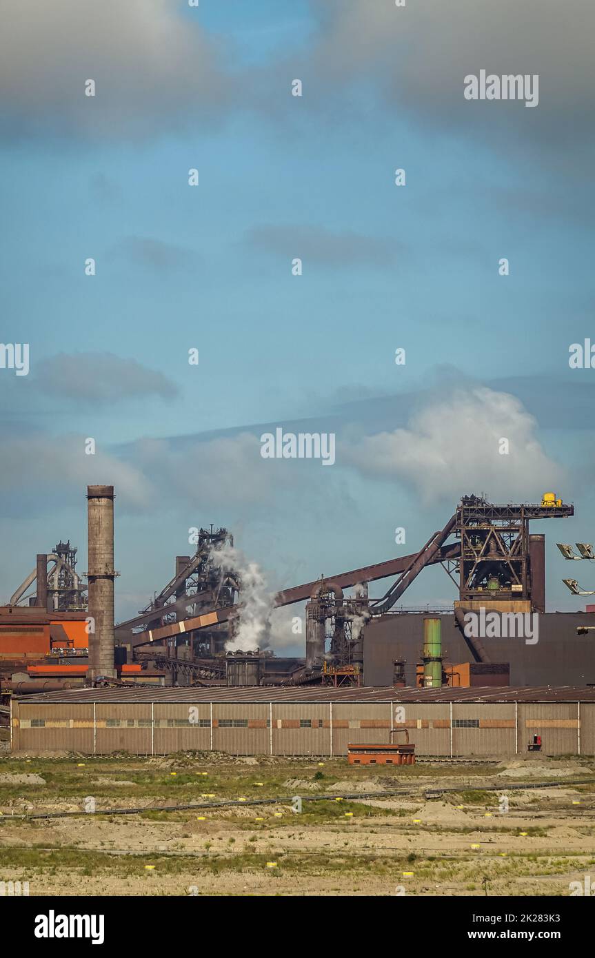 Europe, France, Dunkerque - July 9, 2022: Port scenery. Closeup of coal tranport belt at power generation plant under smokey sky. Large warehouse and Stock Photo