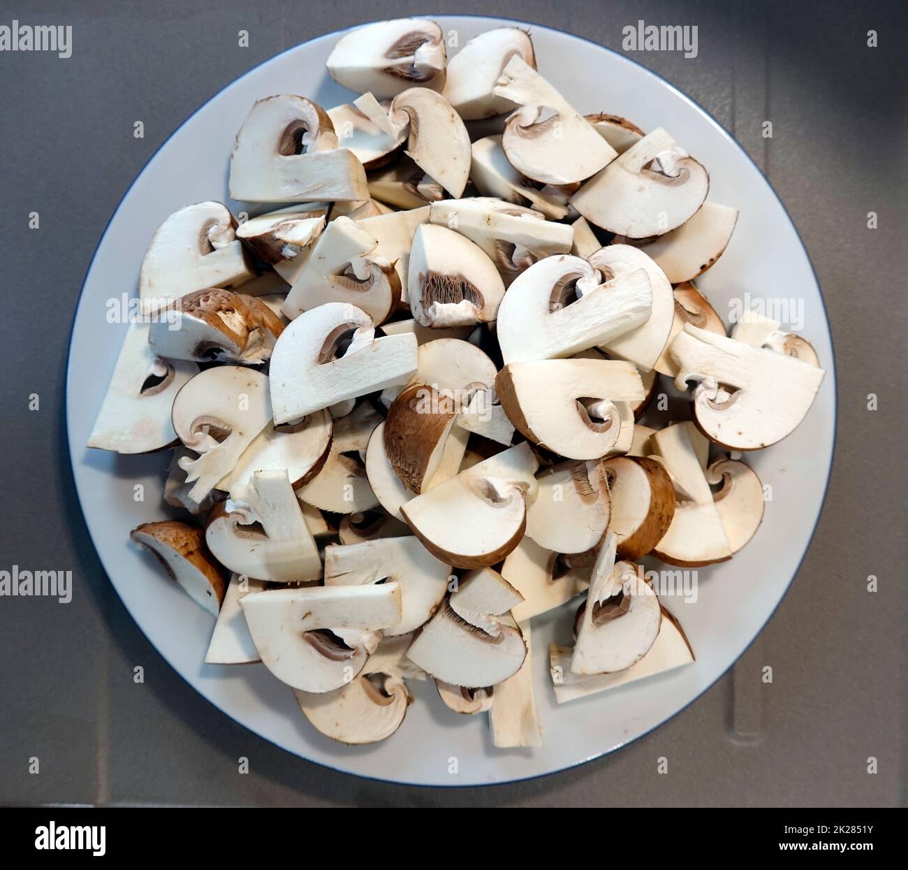 frische Kultur-Champignons liegen geschnitten auf einem Teller, um sie zu braten Stock Photo