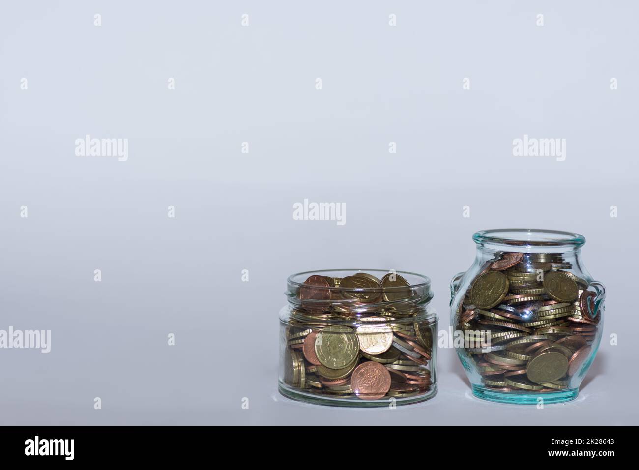 saved money in two  jars with many different euro coins for financial independence with gray Stock Photo