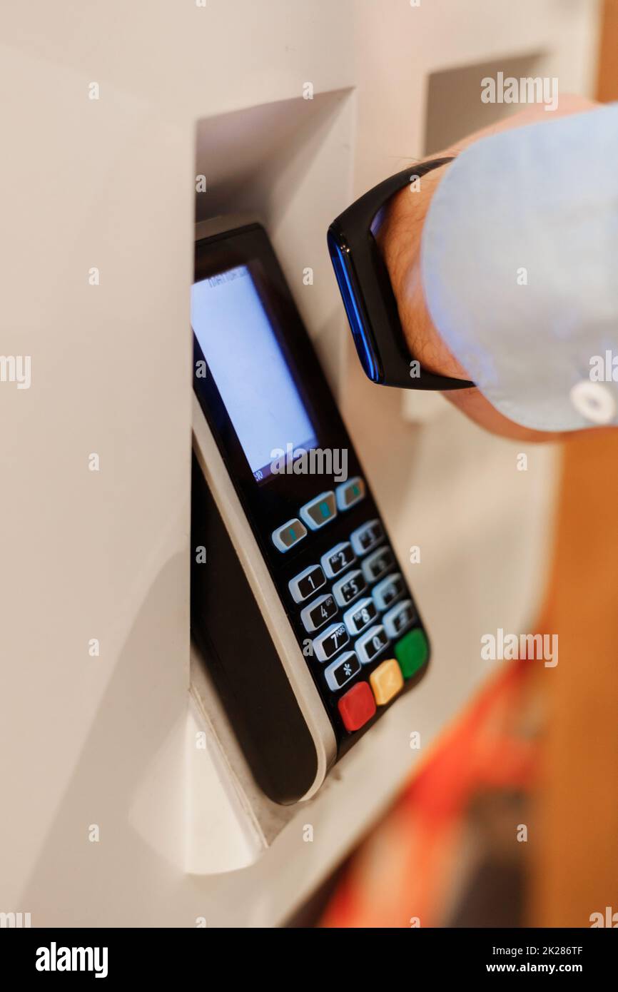 man use smart bracelet to make contactless payment over nfc technology, apply to payment terminal Stock Photo